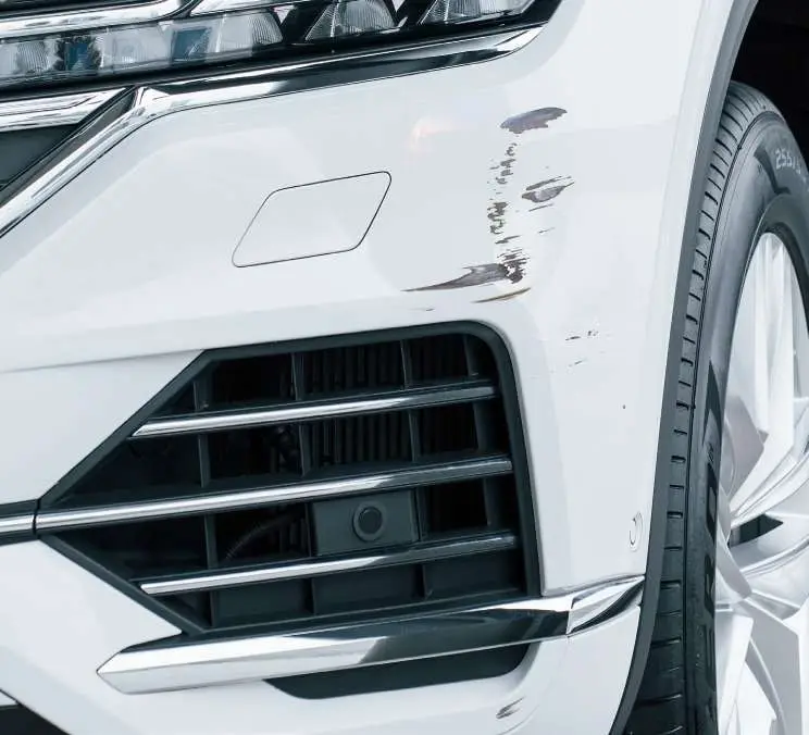 A scuffed white front bumper, before the repair