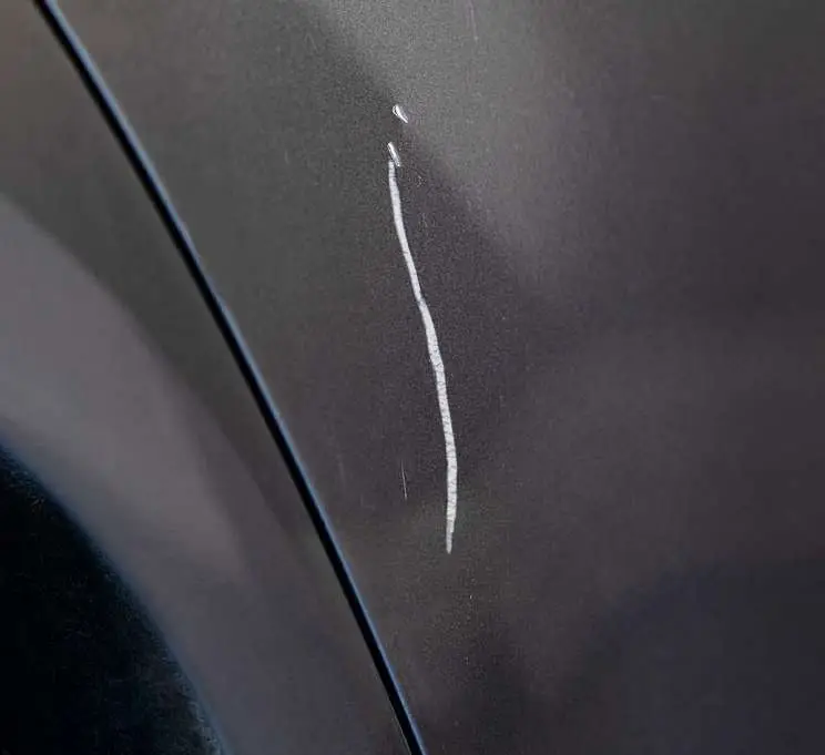 A deep scratch on a grey side panel, before the repair